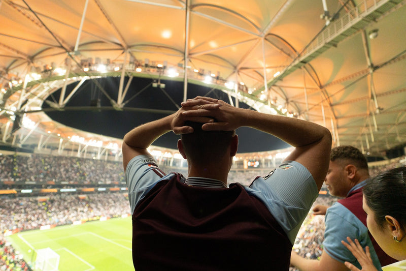 Aston Villa supporter watching from the stands with hands on his head