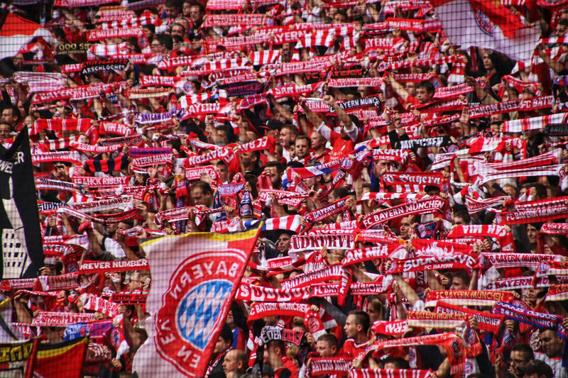 Bayern Munich supporters holding up red-and-white scarves in a packed stand