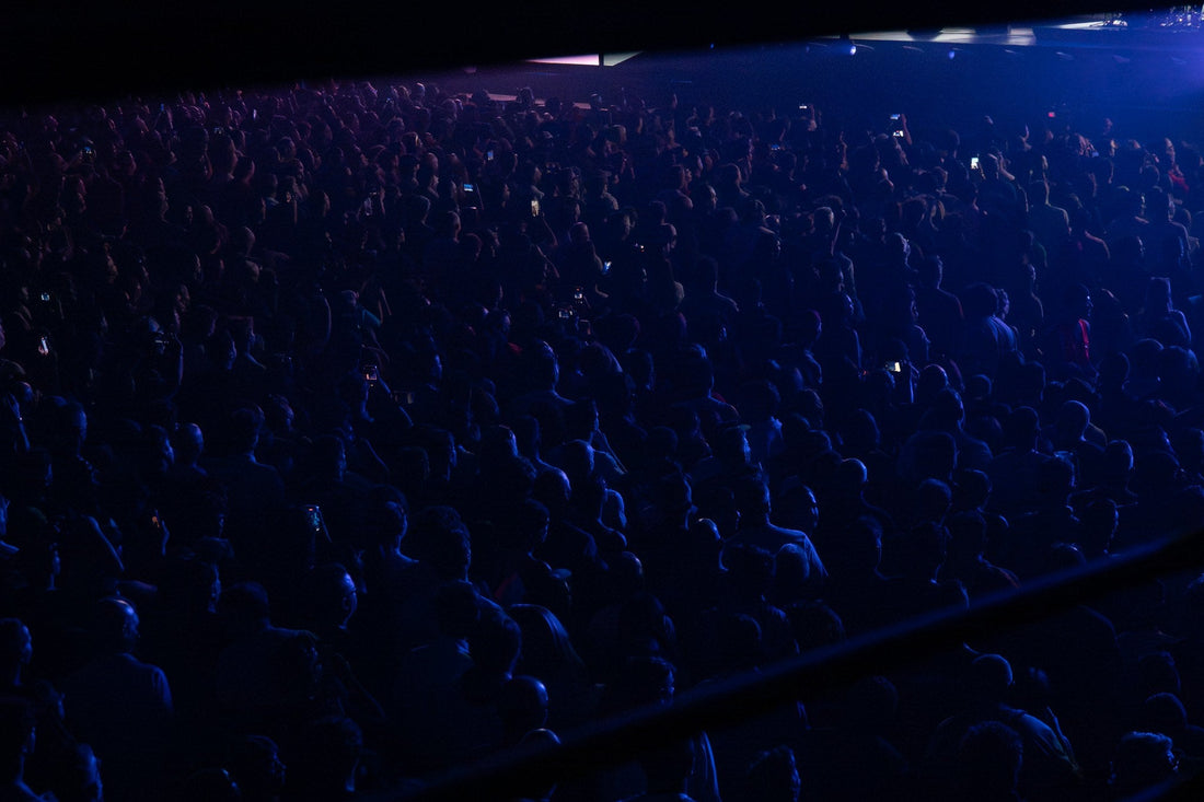 Blue-lit concert crowd seen from a raised side position