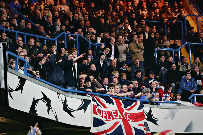 Chelsea fans in the stand above a Chelsea FC Union Jack flag