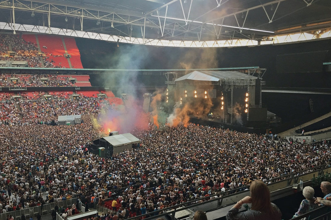 Coloured smoke rises over a packed Wembley Stadium concert crowd