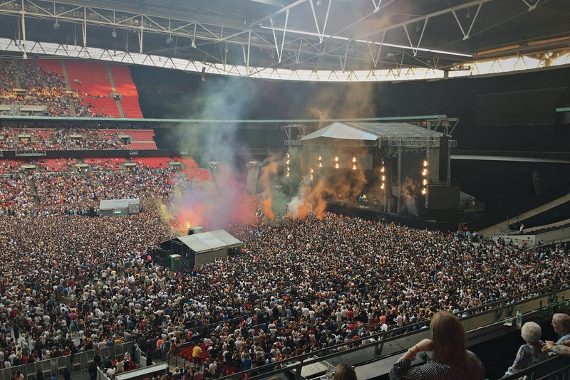Coloured smoke rises over a packed Wembley Stadium concert crowd