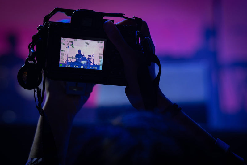 Concertgoer holding up a camera with a drummer on its screen