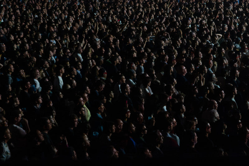 Dense dark concert crowd looking up toward the stage