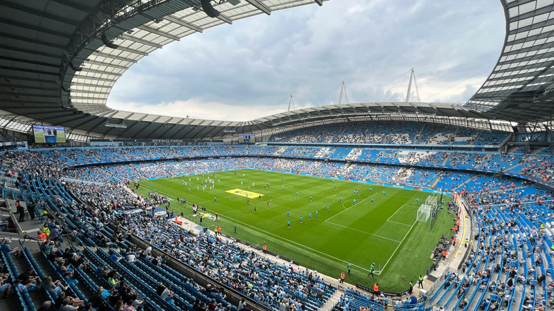 Etihad Stadium bowl in daylight during the pre-match warm-up