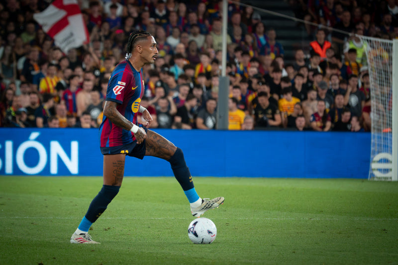 FC Barcelona player on the ball against Athletic Club in La Liga, with a packed home crowd behind the goal