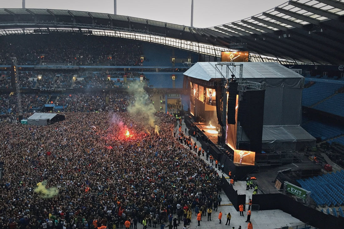 Packed Etihad Stadium floor during a daytime stadium concert