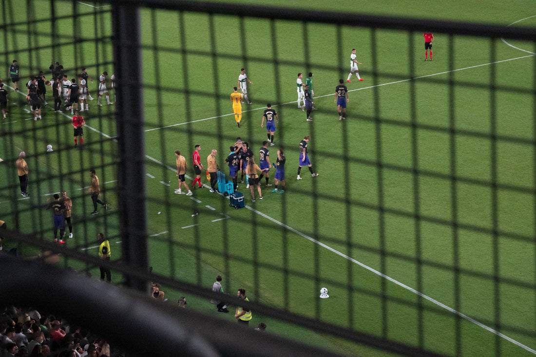 Players and staff on the pitch seen through a perimeter fence