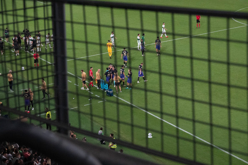 Players and staff on the pitch seen through a perimeter fence