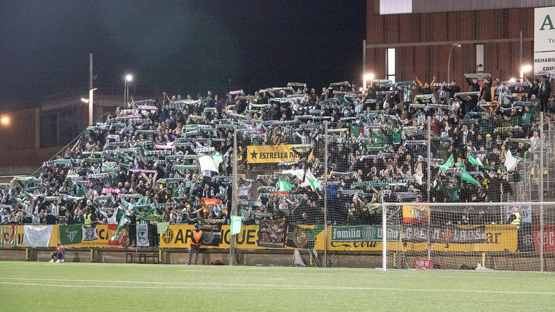 Travelling Real Betis fans hold up green and white scarves in the away end