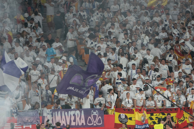 Real Madrid supporters in white fill the away section with flags and banners