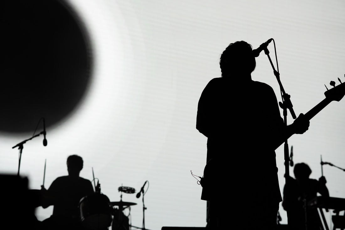 Rock band in silhouette on stage against a bright white backdrop