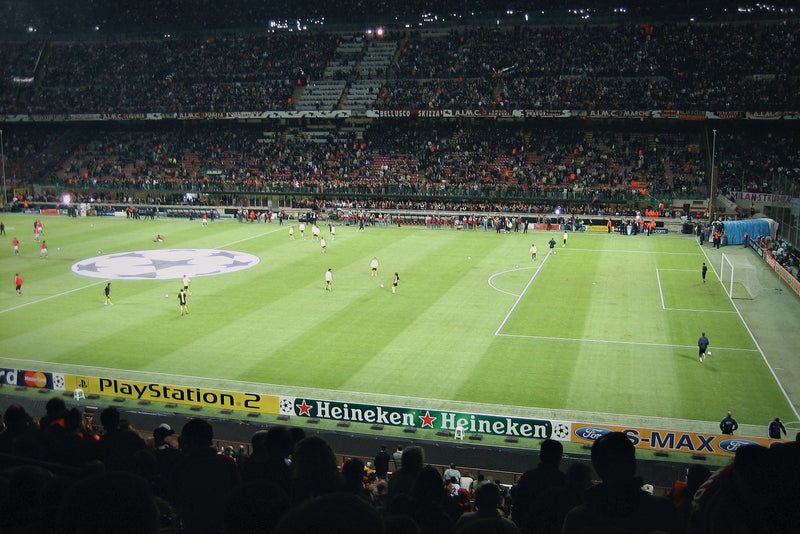 San Siro at night with silhouetted spectators in the foreground
