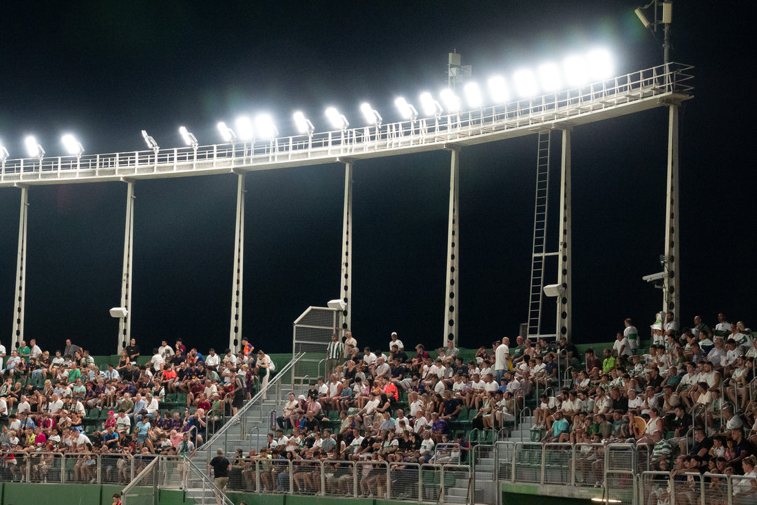 Stadium floodlights blazing over a full stand during a night match