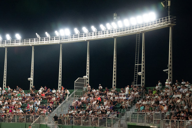 Stadium floodlights blazing over a full stand during a night match