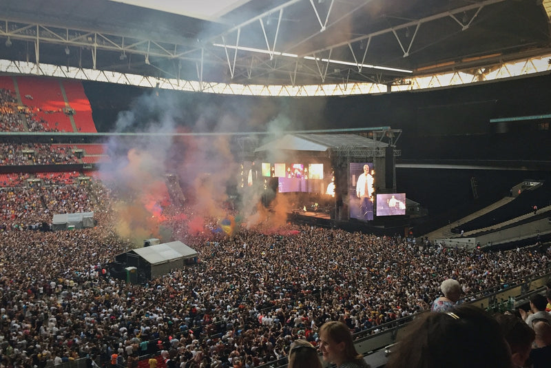 Wembley Stadium concert crowd with coloured smoke in front of the stage
